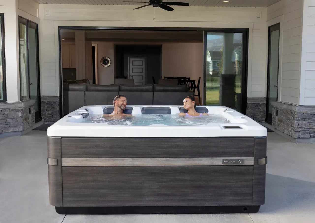 Couple enjoying a Bullfrog A7D spa on a covered patio
